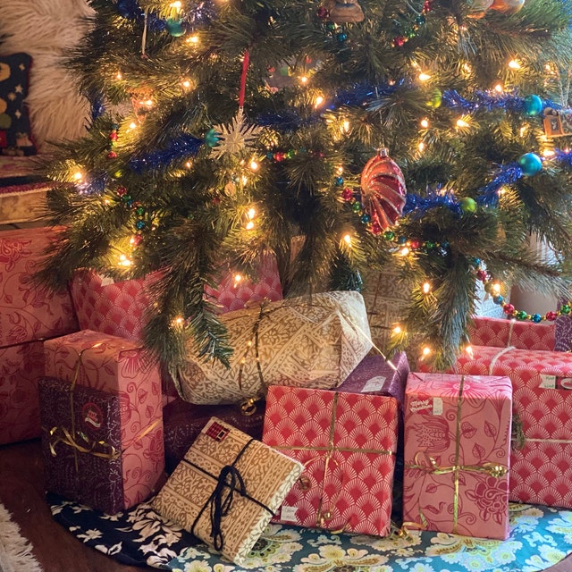 Christmas tree with wrapped presents in red and gold patterns with seed paper gift tags